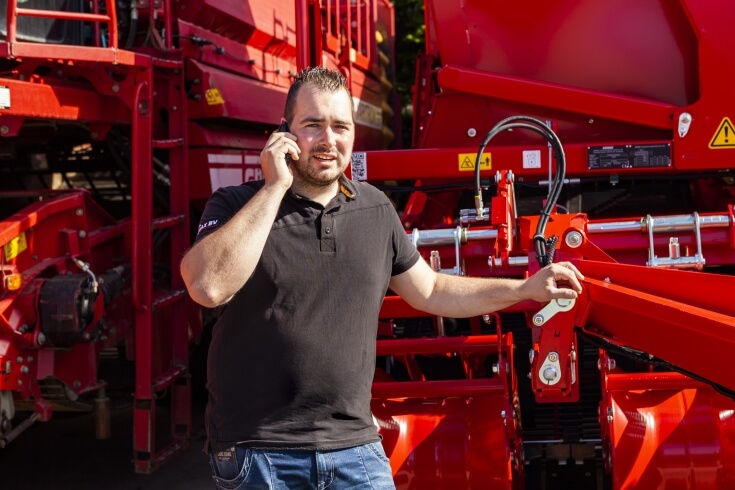 Man belt bij rode landbouwmachine buiten